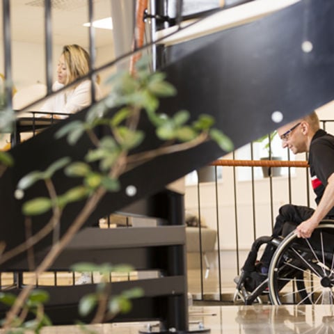 Bild på en av omgivningarna på Campus Västervik. En rullstolsburen person tar sig fram i lokalen.