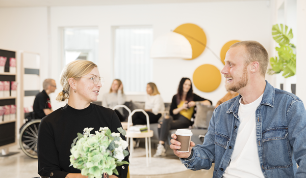 Två glada studenter som sitter vid ett bord och fikar.