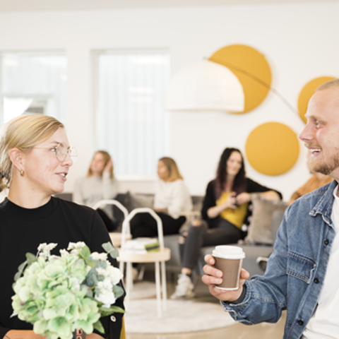 Två glada studenter som sitter vid ett bord och fikar.