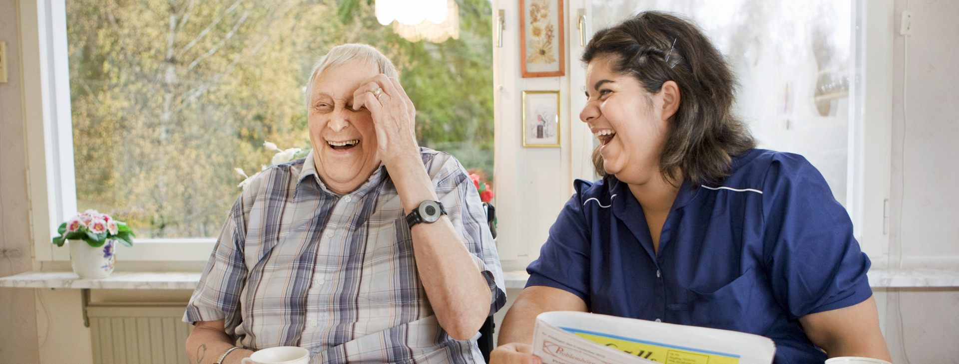 Äldre man och kvinna från hemtjänst skrattar tillsammans.
