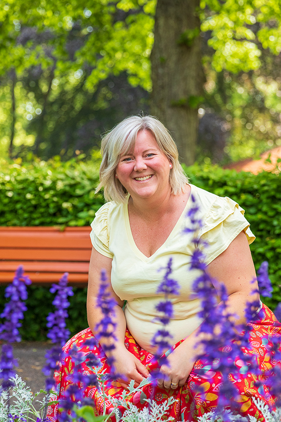 Anna framför sommarblommor.