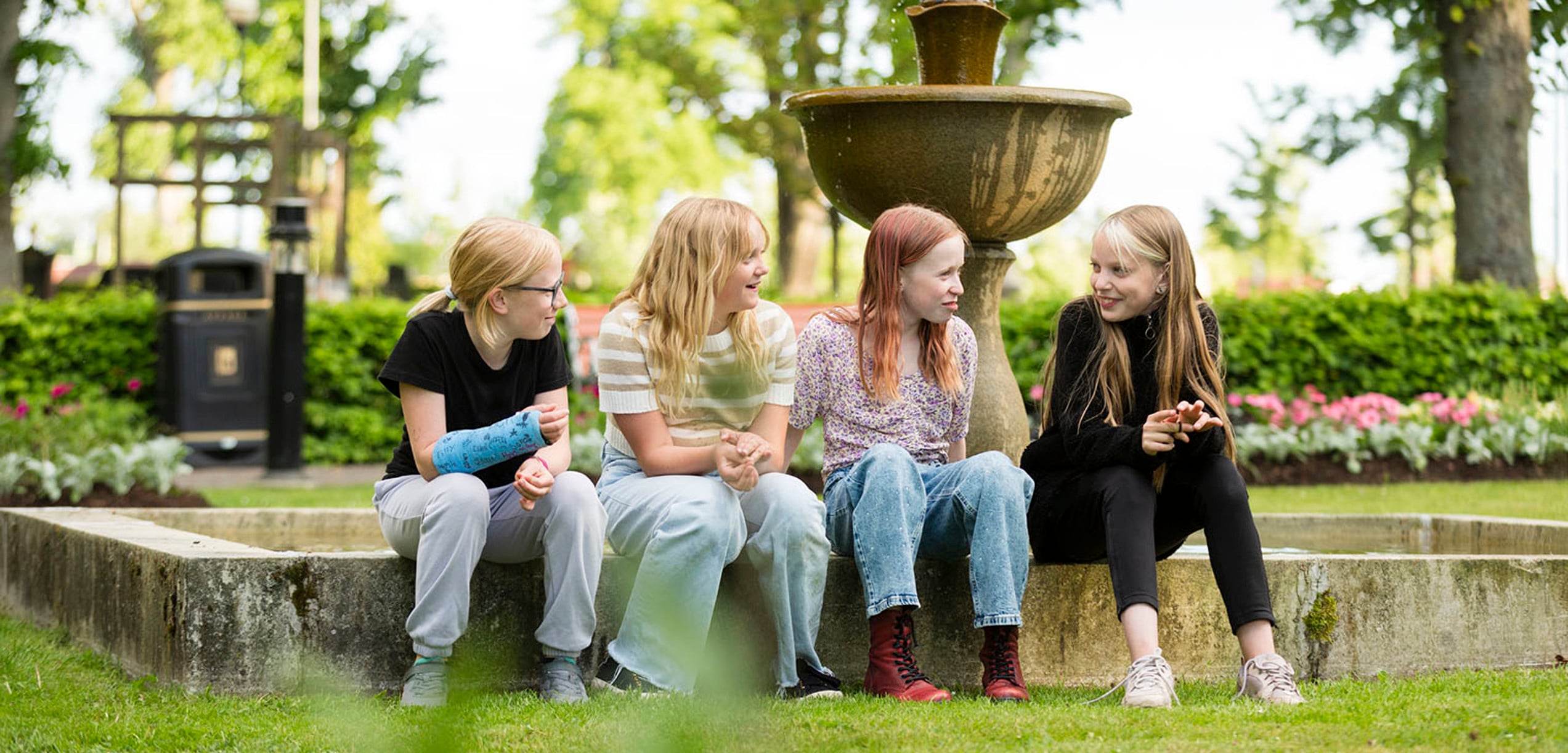 Barn i Stadsparken som sitter vid fontänen och skrattar.