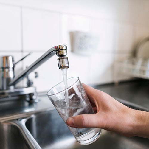 bild på glas som fylls på med vatten ur en kökskran