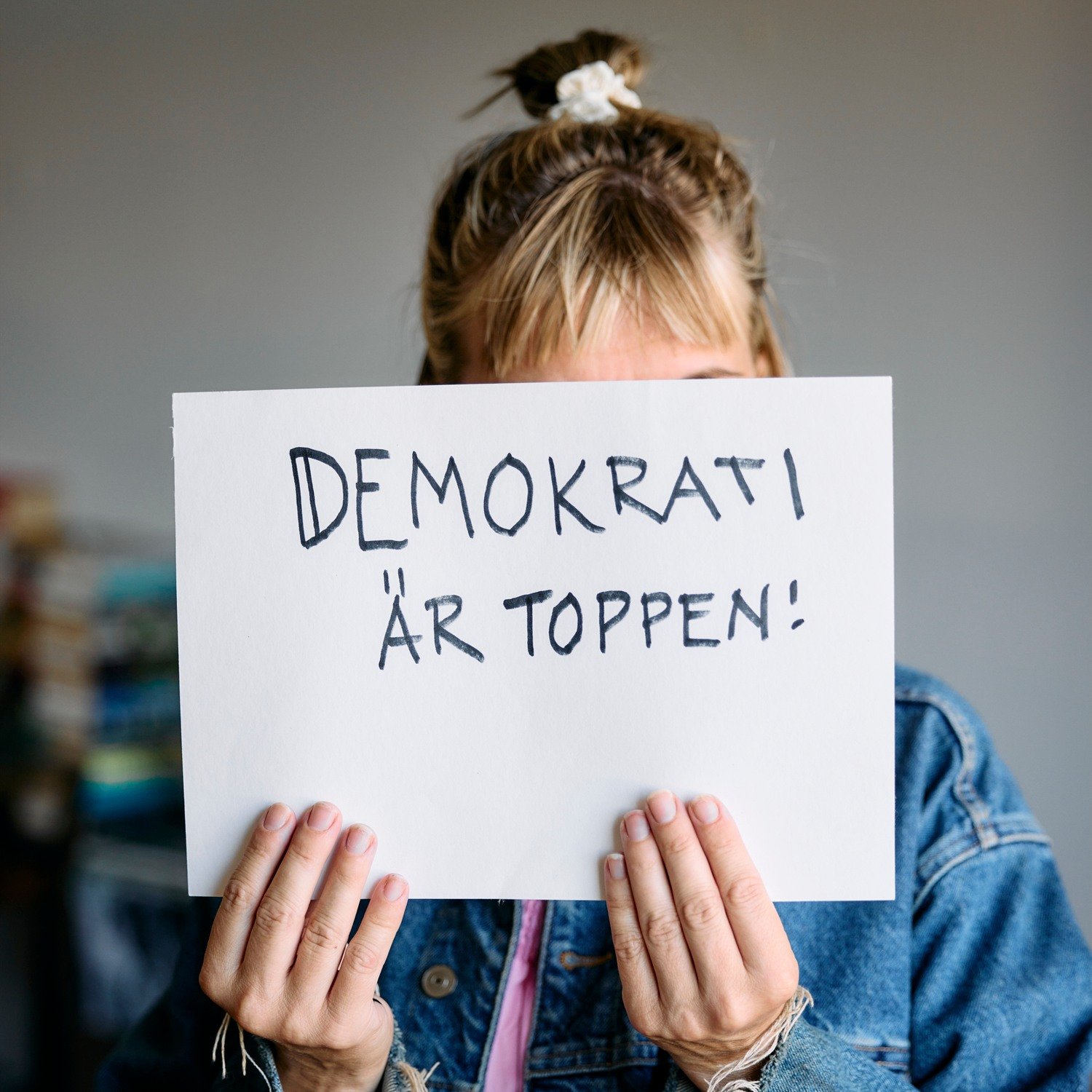 Kvinna som håller upp en skylt med texten Demokrati är toppen.