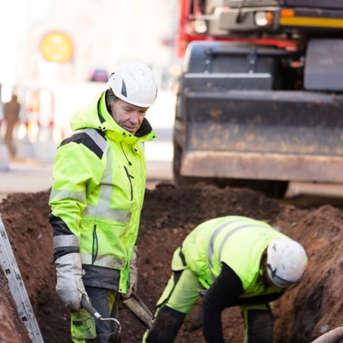 Två personer som arbetar i ett hål i gatan.