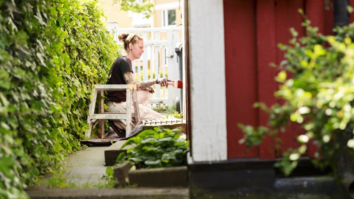 Målare som målar en röd stuga.