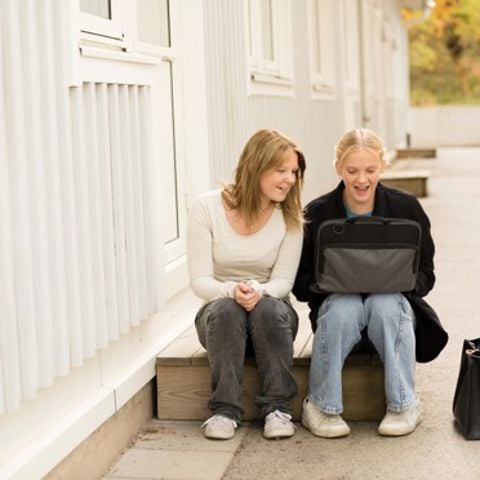 Två tjejer på en skolgård vid en dator.