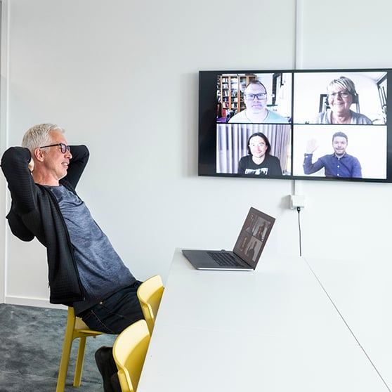 man sittande vid digitalt möte i dator och TV