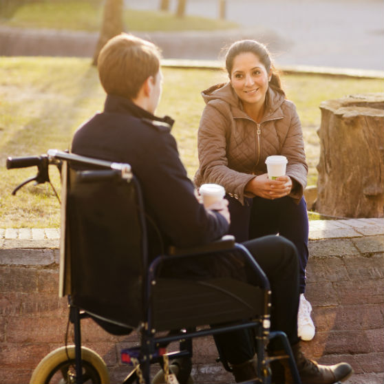 Foto av kvinna som talar med man i rullstol