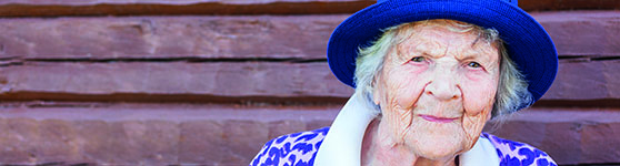 Äldre kvinna i lila hatt utomhus