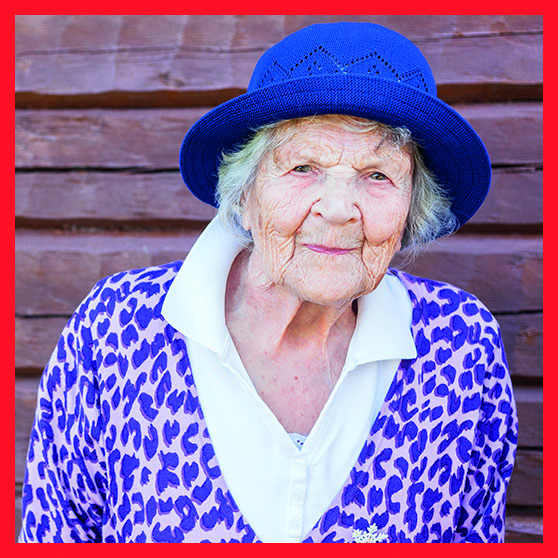 Äldre kvinna med lila hatt utomhus