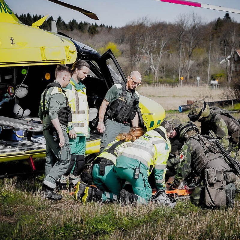 bild från Sjukvårdsövning 24 med sjukvårdare, militärer, helikopter och skådespelare som spelar skadad foto: Försvarsmakten