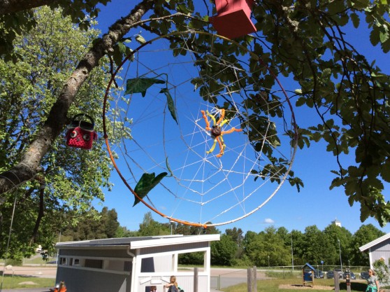 Bild på ett hjul med tråd och spindel hängande i ett träd